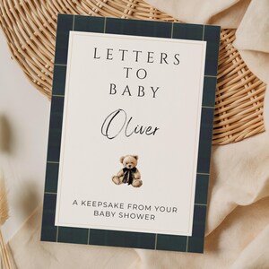 May include: A keepsake baby shower gift, featuring a navy blue and green plaid border. The card reads "Letters to Baby Oliver" with a teddy bear illustration. The text "A Keepsake From Your Baby Shower" is at the bottom.