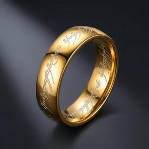 K&ouml;nnte beinhalten: Ein goldfarbener Ring mit eingravierter Schrift. Der Ring hat eine polierte Oberfl&auml;che und eine abgerundete Form. Der eingravierte Text ist in einer kontrastierenden Farbe, wahrscheinlich Silber oder Wei&szlig;, und umschlie&szlig;t das gesamte Band. Der Ring wird vor einem dunklen Hintergrund pr&auml;sentiert.