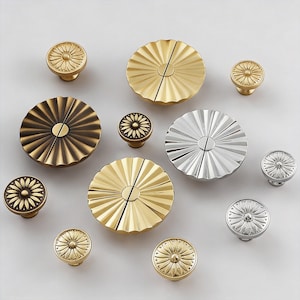 May include: An assortment of decorative cabinet knobs and pulls in various metallic finishes. The collection includes gold, silver, and bronze tones, with designs ranging from floral patterns to fan-shaped details. These hardware pieces are ideal for furniture upgrades.