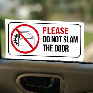 Puede incluir: Una pegatina rectangular blanca con borde negro, que presenta un círculo rojo con una puerta de coche tachada y el texto "PLEASE DO NOT SLAM THE DOOR" en rojo y negro. La pegatina está colocada en una ventana de coche.
