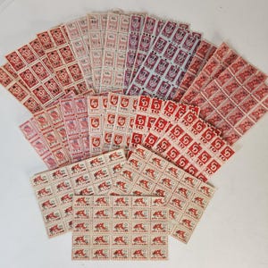 May include: A collection of vintage red and white paper stamps with various denominations, including 10, 60, and 818. The stamps feature different designs, including a red and white bird, a red and white flower, and a red and white geometric pattern. The stamps are arranged in a fan shape on a white surface.