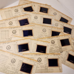 May include: A stack of vintage, yellowed engineering document cards with black rectangular windows. The cards have a seal with the words "Dual Purpose Engineering Document Card" and "USAF" printed on them.
