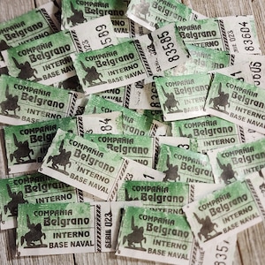 May include: A collection of vintage green and white tickets. Each ticket features the text "COMPANIA Belgrano INTERNO BASE NAVAL" and a silhouette of a person on a horse. The tickets have serial numbers and are slightly worn.