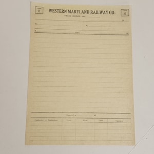 May include: A vintage train order form from the Western Maryland Railway Co. The cream-colored paper has horizontal lines for writing and includes the text "FORM 31" in the upper corners. The form is designed for recording train orders.