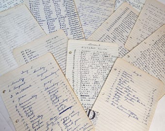 May include: A stack of lined paper notebooks with handwritten notes in blue ink. The notebooks contain lists of words, alphabet sounds, and dates. The pages are slightly worn and have a vintage feel.