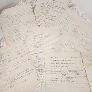May include: A collection of vintage, lined paper sheets filled with handwritten equations, diagrams, and notes. The papers are aged with a yellowed hue, suggesting they are old. The handwriting is in black ink, and some pages have spiral binding.