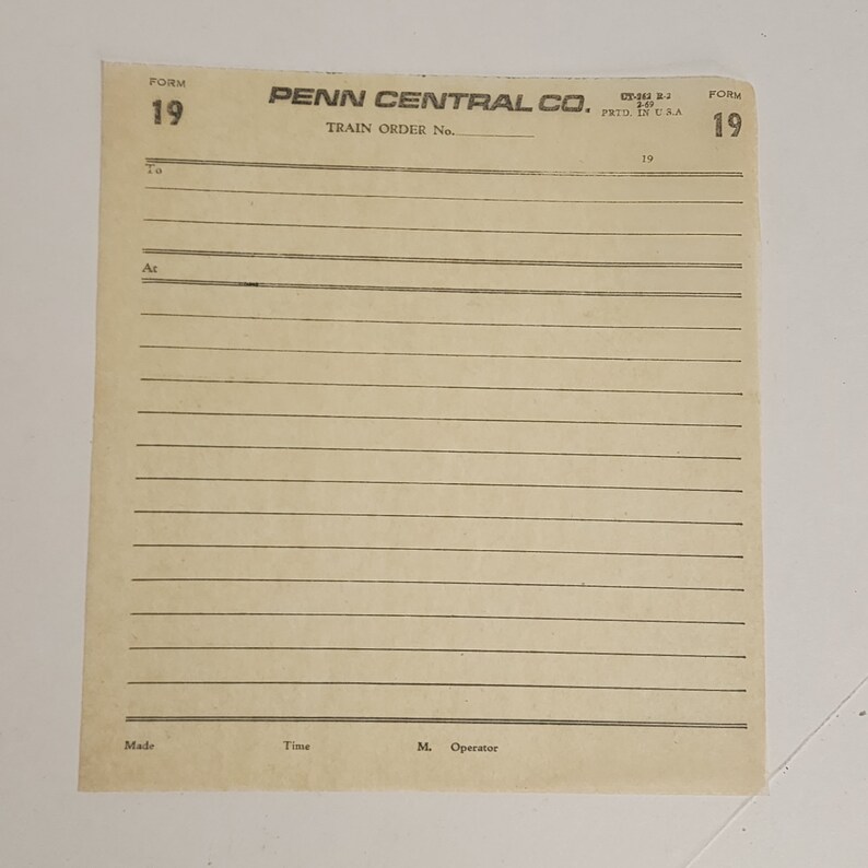 May include: A vintage Penn Central Co. train order form, Form 19, printed in the USA. The cream-colored paper has horizontal lines for writing and includes the text "Train Order No." and "To" and "At".