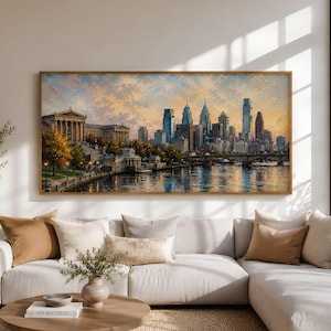 May include: A framed cityscape painting depicts a skyline with tall buildings, a river, and a bridge. The artwork features warm colors, with a focus on the buildings and the water. The frame is a light brown color.