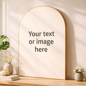 以下が含まれることがあります： 金色のフレームが付いた大きなアーチ型の鏡には「Your text or image here」というテキストが表示されています。 下の木製キャビネットには本、花瓶、植物が置かれ、装飾的なディスプレイを形成しています。 キャビネットは明るい色の木材で作られています。