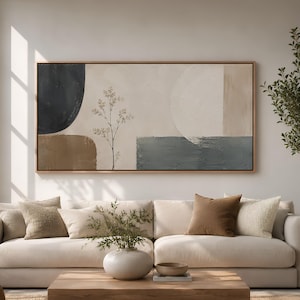 May include: A large rectangular wall art piece featuring abstract shapes in navy blue, beige, and brown, with a delicate botanical line drawing of a plant stem centered on a textured cream background, all enclosed in a thin light wood frame.