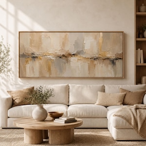 Puede incluir: Una gran pieza de arte mural rectangular y horizontal que presenta un paisaje abstracto con pinceladas de impasto gruesas y texturizadas en tonos crema, beige, gris suave y oro metálico, enmarcada en un marco de madera natural clara.