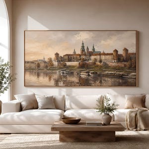 May include: A large rectangular landscape painting in a thin wooden frame depicting a historic city skyline with towers and stone walls along a riverbank, featuring warm beige, brown, and soft orange tones with visible textured brushstrokes.
