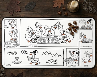 Può includere: Un tappetino da gioco rettangolare bianco con disegni a linee nere di anatre che indossano cappelli da mago. Il design include sezioni etichettate per Life Total, Commander, Battlefield, Library, Lands, Graveyard ed Exile, con varie illustrazioni.