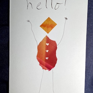 May include: A handmade greeting card with the word "hello!" written in black ink. The card features a whimsical figure made of torn paper in shades of red and orange, with a yellow diamond-shaped head. The figure has stick arms and legs.