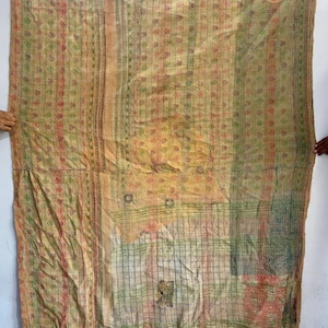 May include: A large, rectangular, multi-colored textile with a patchwork design. The textile features a mix of colors, including yellow, green, red, and orange. The fabric has a textured appearance with visible stitching and a faded aesthetic. The tag in the upper left corner reads "VQ1451".