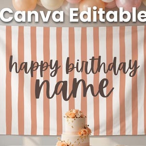 May include: A birthday party backdrop with vertical peach and white stripes, featuring the text "happy birthday name". A two-tiered cake with floral decorations sits in front of the backdrop, with balloons in shades of peach and white.