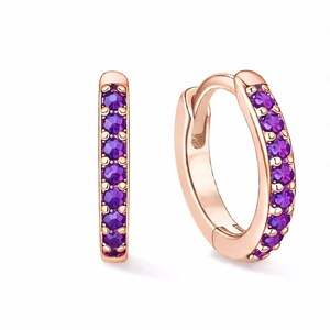 May include: Rose gold hoop earrings, each adorned with small, round, purple gemstones. The earrings are set against a white backdrop, accentuating their design and colour. A classic jewellery item.