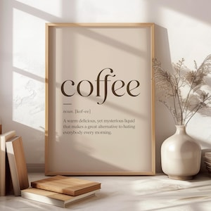 May include: A framed wall art print featuring the word coffee in a large serif font, followed by the phonetic spelling kof-ee and a definition describing it as a warm liquid that serves as an alternative to hating everyone every morning.