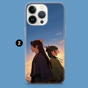 May include: Clear phone case featuring an anime-style illustration of two figures standing back-to-back against a sunset backdrop. The figures are dressed in traditional clothing, with long hair and a serene expression. The case has a glossy finish.