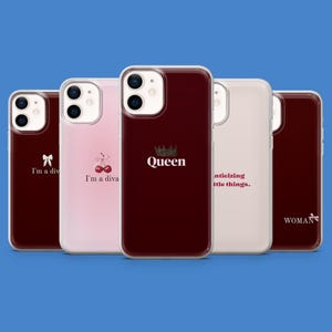 Peut inclure: Plusieurs coques de téléphone de couleurs variées, chacune avec des motifs et du texte uniques. Les coques comprennent une coque rouge foncé avec une couronne et le mot "Queen", une coque rose avec des cerises et le texte "I'm a diva", et une coque blanche avec le texte "anticipating little things."