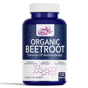 May include: A dark blue bottle of Fitness Veda Organic Beetroot dietary supplement. The label includes text promoting liver detoxification, heart health, and blood circulation. The bottle contains 120 veggie caps.