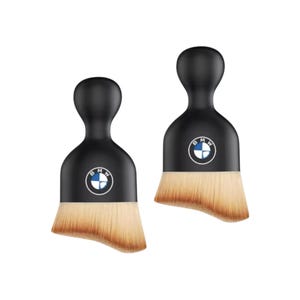May include: Two black makeup brushes with a rounded handle and a flat, angled brush head. Each brush features the BMW logo in the centre. The brush heads are light brown.