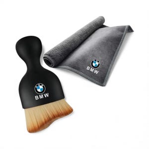 May include: A black car detailing brush with a BMW logo and a gray microfiber towel with a rolled-up section. The brush has a curved handle and tan bristles. The towel also features the BMW logo.