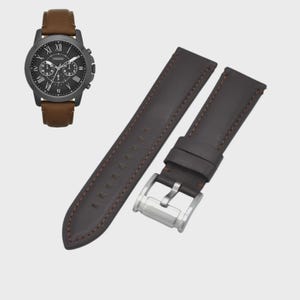 May include: A black chronograph watch with a brown leather strap and a separate brown leather watch strap. The watch has Roman numeral hour markers and three sub-dials. The watch strap is brown with brown stitching.