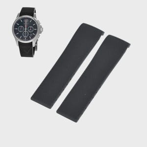 May include: A silver-toned wristwatch with a black dial and a black leather strap is displayed next to two black watch straps. The watch has three sub-dials and a date window. The watch straps are textured.