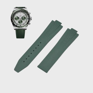May include: A silver wristwatch with a white face and green accents, paired with a set of dark green watch straps. The straps are made of a textured material and have a classic design. The watch has a green strap.