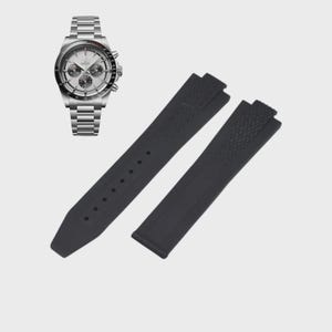 May include: A silver-toned chronograph watch with a white face and three sub-dials, paired with a black rubber watch strap. The watch features a stainless steel band. The black strap has a textured pattern.