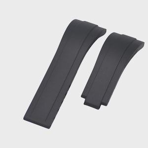 May include: Two black watch straps, curved and slightly textured, are shown against a light grey background. The straps are made of a flexible material and are designed to attach to a watch case. The straps are new and unused.