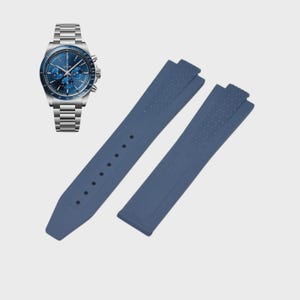 May include: A stainless steel watch with a blue face and a matching blue rubber watch band. The watch band is in two pieces, with a textured pattern on the ends. The watch has a metal band.