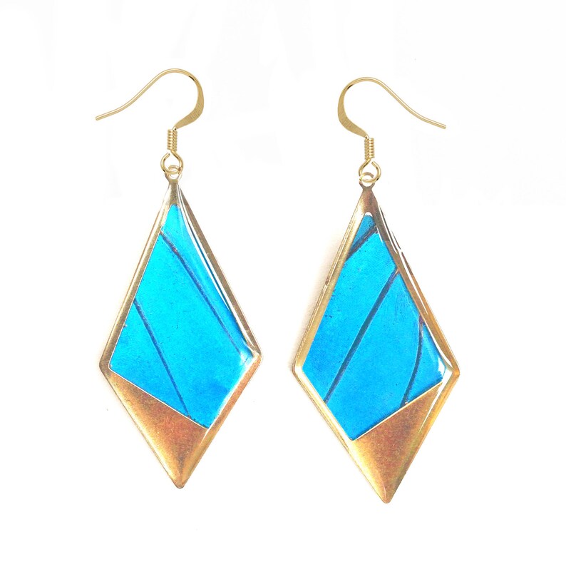 May include: A pair of gold earrings with blue butterfly wings encased in a diamond-shaped frame.