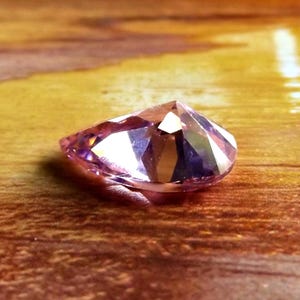 Face down in a wet sandy sea setting, showing the pointy back, ready to be made into jewelry