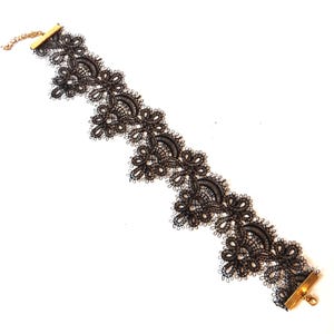 Black lace choker necklace with a gold clasp. The lace is delicate and intricate, with a floral pattern.