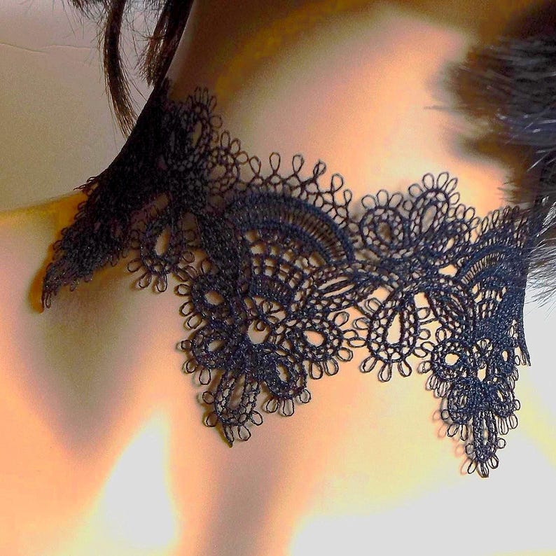 May include: A black lace choker necklace with an intricate floral design. The delicate openwork pattern creates a detailed and elegant look. The choker is designed to sit around the neck, adding a touch of sophistication.