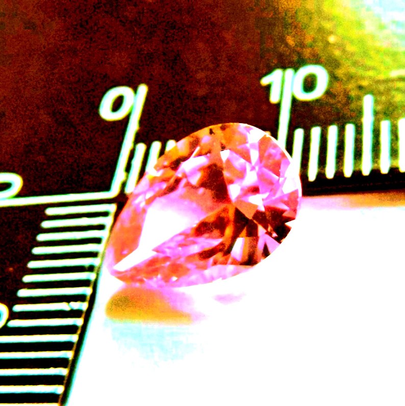 Next to a ruler 8x12mm pink pear cut CZ gemstone