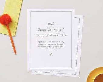 May include: A stack of white paper workbooks with the title "Same Us, Softer" and the year 2026. An orange pen with a fluffy pom-pom top and a yellow notepad are on the left. A yellow saucer with a cup is on the bottom right.