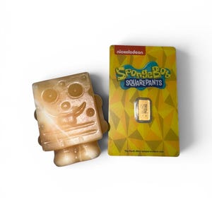 May include: A light-colored, translucent SpongeBob SquarePants figurine next to a gold bar in a yellow Nickelodeon-branded package. The package features the SpongeBob SquarePants logo and text.