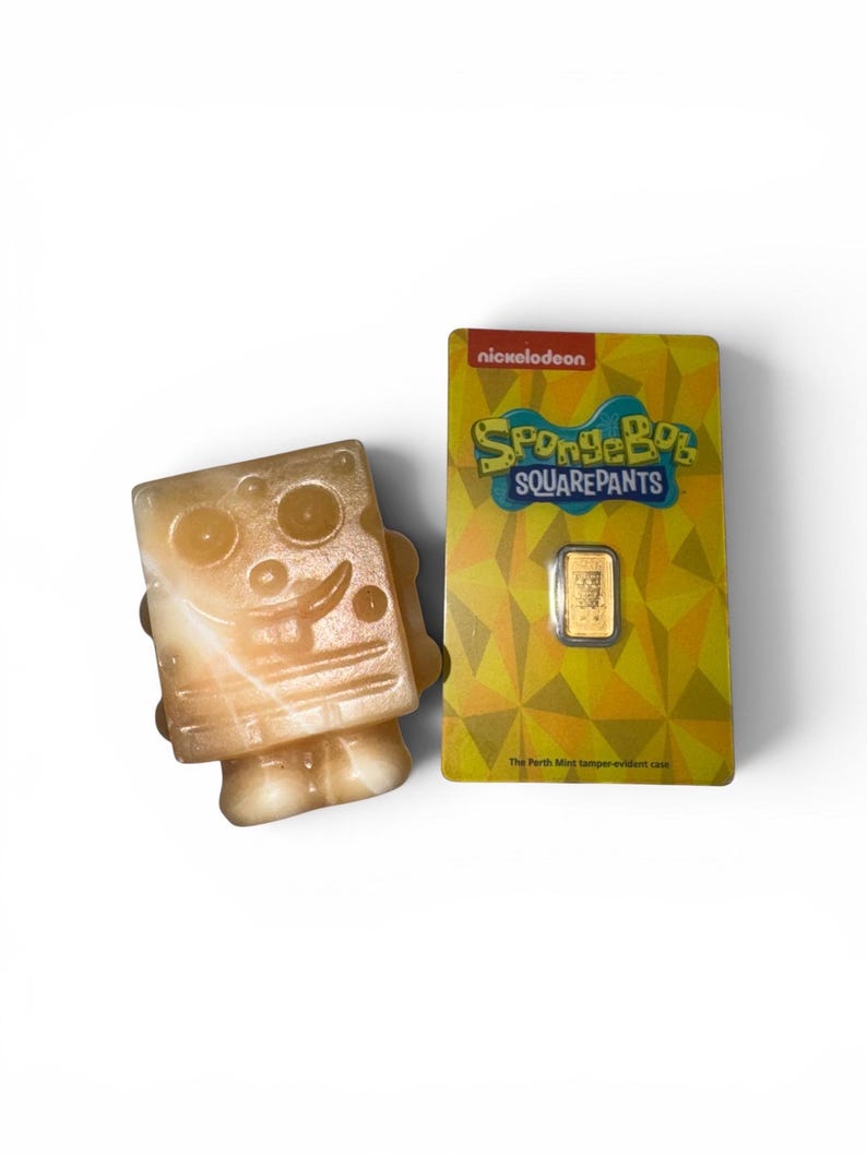 May include: A light-colored, translucent SpongeBob SquarePants figurine next to a gold bar in a yellow Nickelodeon-branded package. The package features the SpongeBob SquarePants logo and text.