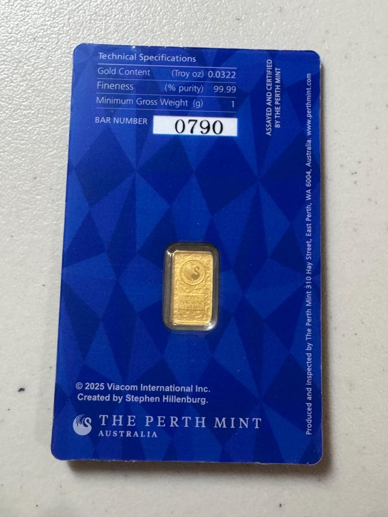 May include: A gold bar from The Perth Mint, displayed on a blue card. The card includes technical specifications, the bar number 0790, and the Perth Mint logo. The gold bar has a swan design.