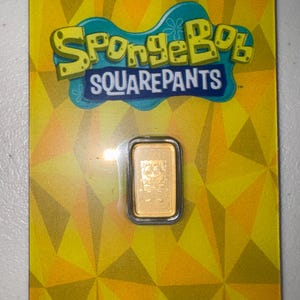 May include: A gold bar featuring SpongeBob SquarePants in a tamper-evident case. The packaging is yellow with a geometric pattern and the Nickelodeon and SpongeBob SquarePants logos. The text "The Perth Mint tamper-evident case" is visible.