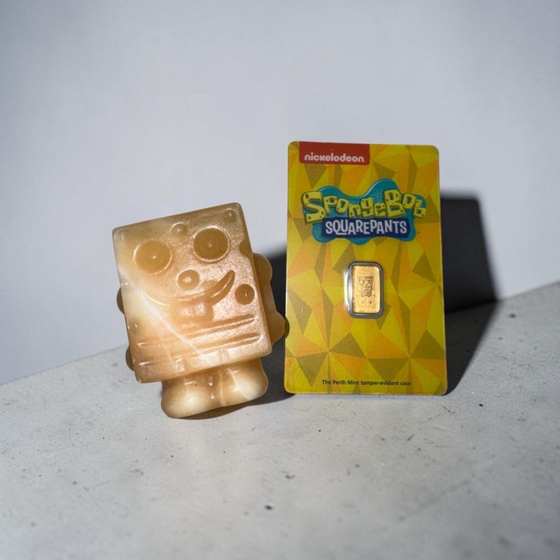 May include: A light-colored, square-shaped figurine of SpongeBob SquarePants next to a gold bar on a yellow card with the SpongeBob SquarePants logo. The card also has the Nickelodeon logo.