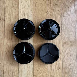 May include: A white ceramic mug with a black handle and the text "But First, Coffee" in a handwritten style. The mug is likely for hot beverages and has a glossy finish.