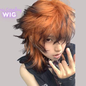 May include: A cosplay wig with a layered, shaggy style. The wig features a blend of orange and black colours, creating a striking contrast. The text "Epic Cosplay WIG" is visible in the upper left corner.