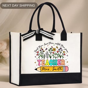 May include: White tote bag with black trim and handles. The bag features a colorful graphic with the word "TEACHER" and a pencil illustration. Text above the graphic reads "Teach them, love them, watch them grow." The bag includes the text "Mrs. Smith".