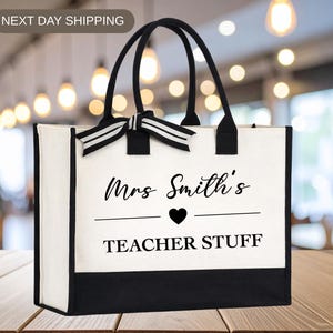 May include: White and black tote bag with black handles and a striped bow. The bag features the text "Mrs Smith's TEACHER STUFF" with a heart symbol. A perfect gift for teachers.