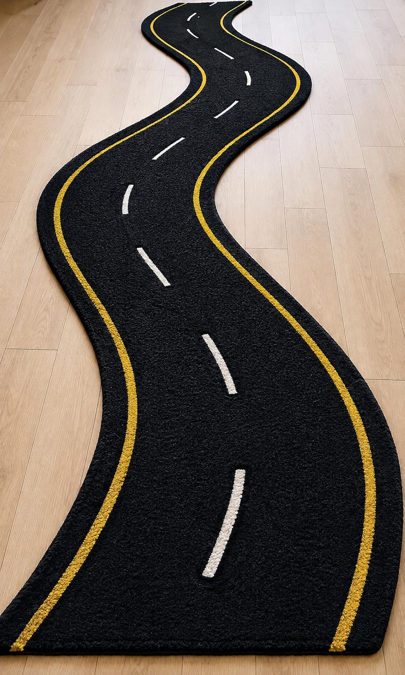 以下が含まれることがあります： 道路の形をした長く曲がりくねった黒いラグ。ラグの端には2本の連続した黄色の線があり、中央には白い破線が並んでおり、高速道路や車線の標示のような外観を模しています。