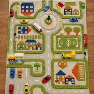 May include: A rectangular area rug featuring a colorful city map design with gray roads, green grass patches, and various buildings including houses and a restaurant. The rug includes toy cars, a bus, and a truck placed on the road sections.